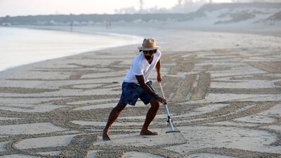 Sand artist Nathaniel Alapide draws murals on the beach using a rake in Jebel Ali. Chris Whiteoak / The National