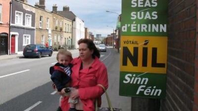 A mother and child in Dublin walk past a poster urging a "no" vote in the treaty poll. It reads in Gaelic: "Stand up for Ireland. Vote no.''