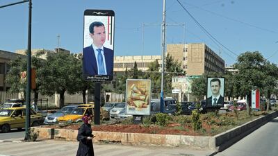 A picture taken through the window of a bus shows a woman standing in a street under the portrait of Syrian president Bashar al-Assad, in an unspecified town in Aleppo province, northern Syria, 18 April 2018. EPA/YOUSSEF BADAWI