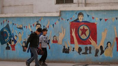 Syrian children carrying food walk in front of a YPG sign in the northwestern city of Afrin, Syria, during a Turkish government-organised media tour. Turkey considers the YPG a terror group and an extension of Kurdish rebels waging an insurgency within its own borders. Lefteris Pitarakis / AP