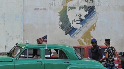 A vintage car with a US flag and graffiti of revolutionary leader Ernesto 'Che' Guevara in Havana / AFP