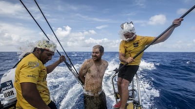 Matt Knighton, centre, crossed the Equator for the first time, and pays tribute to King Neptune, as all "Pollywogs" should do when crossing the imaginary line for the first time. The rest of the crew who has passed the Equator before are called "Shellbacks", in this image represented by Adil Khalid, left, and Justin Slattery. Matt Knighton / Abu Dhabi Ocean Racing