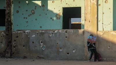 A student reads a book while leaning against a wall of the Maar Shmarin Primary School, its surface scarred by bullet holes from the fighting between forces loyal to former President Bashar Assad and rebel groups, in the village of Maar Shmarin, in the Idlib countryside, Syria. AP