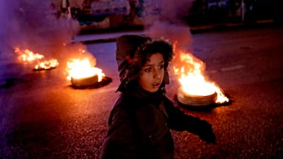 A Lebanese child walks by burning tyres during a rally by supporters of outgoing prime minister Saad Hariri. AFP