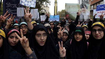 Iranian schoolgirls flash the victory sign in front of the former US embassy in an annual gathering to mark its 1979 takeover, while a surface-to-surface Sejjil missile is displayed by the Revolutionary Guard behind them in Tehran on November 4, 2017. Vahid Salemi / AP