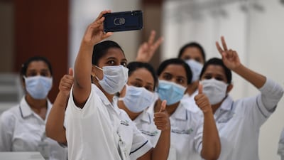 Nursing staff flash victory signs for a selfie, as they set up a huge field hospital at Dubai World Trade Centre. The facility's huge halls, typically used for exhibitions and conferences, can hold up to 3,000 beds. All photos by Karim Sahib / AFP