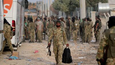 A Turkey-backed Syrian rebel fighter walks as he holds a bag and a weapon in the border town of Akcakale in Sanliurfa province, Turkey. Reuters