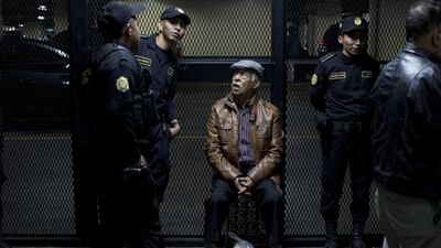 Edilberto Letona Linares, a former army officer, sits surrounded by police after arriving to a courtroom in Guatemala City. Moises Castillo / AP Photo