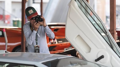A visitor documents one of the many unique cars on display in the Classic Cars Parking area