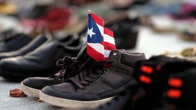 View of a Puerto Rican flag placed on a pair of shoes among hundreds displayed in memory of those killed by Hurricane Maria in front of the Puerto Rican Capitol, in San Juan. Ricardo Arduengo / AFP