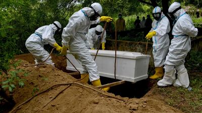 Gravediggers lower a coffin during a funeral for a Covid-19 coronavirus victim at a cemetery in Kajhu, Aceh province. AFP