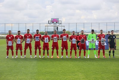 Iranian national team players hold photos of children said to have been killed in a US strike. AFP