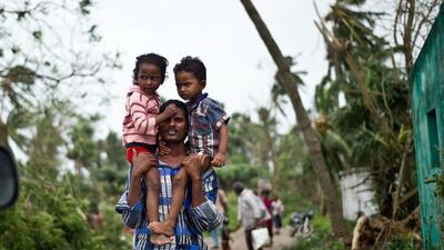 A displaced Indian man carries his children at Sonupur village near Gopalpur following the biggest evacuation in India’s history as Cyclone Phailin approached. Manan Vatsysyana / AFP