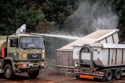Men in hazmat suits desinfect truck containers as members of Danish health authorities assisted by members of the Danish Armed Forces dispose of dead mink. AFP