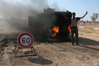 A member of the Libyan National Army flashes a victory sign next to a burning tank after clashes to recover oil ports in Ras Lanuf, Libya June 21, 2018. Picture taken June 21, 2018. Reuters/Stringer.