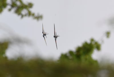 A Battle of Britain Memorial Flight flypast of a Spitfire and a Hurricane passes over the home of Second World War veteran Captain Tom Moore, to mark his 100th birthday in Marston Moretaine, England, Thursday April 30, 2020. Captain Tom has become a national hero figure having raised more than 29 million pounds (36 million dollars) for the National Health Service by walking laps around his garden ahead of his 100th birthday, during the national lockdown in response to the highly contagious COVID-19 coronavirus epidemic. (Joe Giddens / PA via AP)