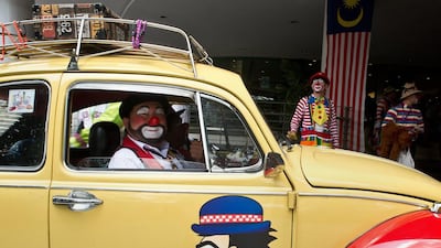 A Malaysian clown named Mr Potato, centre, drives his Beetle during the Clown Festival.