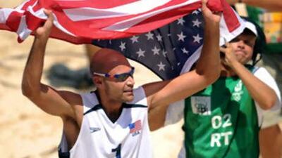 Phil Dalhausser of the USA runs with the US flag as he celebrates his team's victory over Brazil