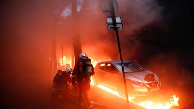 Firefighters work next to a car surrounded by flames during a protest against the "Global Security Bill'' in Paris, France, December 5, 2020. Gonzalo Fuentes / Reuters