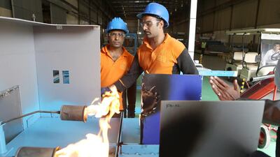 Workers do a fire test on different types of sheets at the Mulk Holdings facility at Hamiryah Free Zone. Pawan Singh / The National