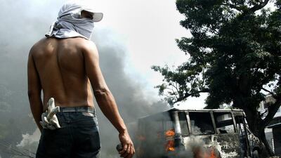 An anti-government protester holds a stone in front of a burning bus during a protest against Nicolas Maduro’s government in San Cristobal. Carlos Eduardo Ramirez / Reuters