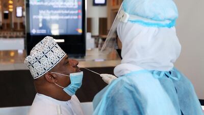 A medical worker collects a swab sample from a passenger at Muscat international airport in the Omani capital on October 1, 2020. AFP