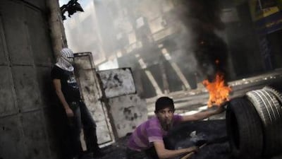 A Palestinian demonstrator during clashes with the Israeli army in Hebron yesterday. Palestinians across the West Bank and Gaza observed a general strike over the death of an inmate in an Israeli jail.