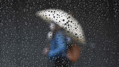 Raindrops are seen on a taxi window while a woman passes by a closed store in Buenos Aires. AFP