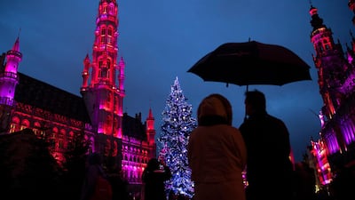 People walk near a Christmas tree in downtown Brussels, Belgium. AP Photo