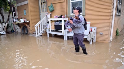 A resident carries his dog from their flooded home in the Pajaro area of Watsonville, California