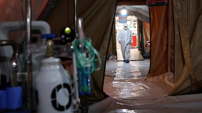 A person in protective clothing walks through a temporary 2,000-bed hospital for COVID-19 coronavirus patients. AP Photo