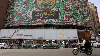 Iranians drive past a billboard in Tehran's Valiasr square with a slogan reading in Farsi: "Army is sacrifice itself for the nation". AFP
