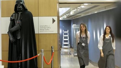 Christie's employees walk past a Darth Vader costume from the Star Wars movie anthology.