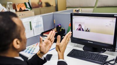 A Sanad Relay Centre interpreter talks with an executive at Dubai Immigration Authority who is hearing impaired. Alex Atack for The National