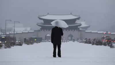 A man uses an umbrella on January 20, 2017 against the snow near the Gwanghwamun — the main gate of the 14th-century Gyeongbok Palace — a South Korea landmark, in Seoul. Lee Jin-man / Associated Press