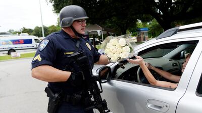 Baton Rouge police officer Randy Bonaventure takes a bouquet of flowers at the Our Lady of the Lake Hospital, where the police officers were brought on Sunday. Three police officers were killed and wounded Sunday morning in a shooting near a gas station in Baton Rouge. Henrietta Wildsmith / The Times via AP