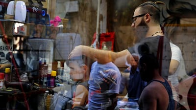 In this Friday, July 14, 2017 photo shot through a window, Muhannad Khaled Omar, right, prepares to create an image of U.S. President Donald Trump on the back of a customer's head at his barber shop in Burj al-Barajneh, southern Beirut, Lebanon. In a city full of hair stylists, Omar stands out. He is a 26 year-old Palestinian-Syrian hair stylist known for shaving celebrity portraits into clients’ hair. (AP Photo/Bilal Hussein)