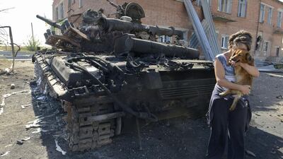 A woman holds a dog beside a destroyed tank in the courtyard of the local kindergarten in the village of Talakovka, some 22 kilometres northeast of Mariupol, on September 6, 2014, a day after Kiev and pro-Russian rebels signed a ceasefire after five months conflict which has plunged relations between Russia and the West into their worst crisis since the Cold War. . Alexander Khudoteply/AFP Photo