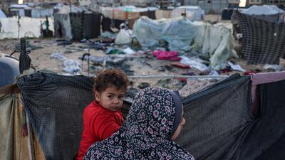 A woman holds a child near the site of Israeli bombardment on tents sheltering displaced Palestinians in Khan Younis, southern Gaza. AFP