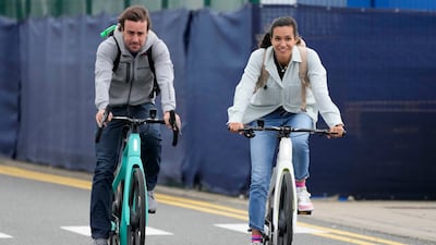 Alpine driver Fernando Alonso, left, and partner Anbdrea Schlager arrive by bicycle. AP