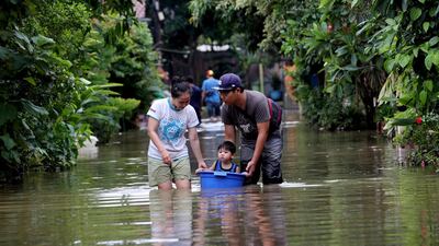 A family walks their son in a bucket through Tanggerang. AP
