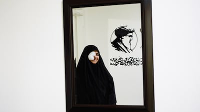 Zeinab Mestrah, 26, who was wounded in the pagers attack carried out by Israel last September, is seen reflected in a mirror at the spot where she was injured, in Beirut's southern suburb of Dahiyeh, on April 25. A portrait of the slain Hezbollah leader Hassan Nasrallah hangs on the wall above her. AP