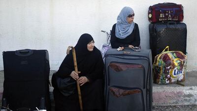 Two Palestinian women hoping to cross into Egypt wait with suitcases at the Rafah crossing between Egypt and the southern Gaza Strip.
