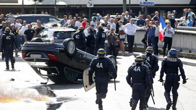 French riot police stand next to an overturned car as striking taxi drivers block traffic on the Paris ring road during a national protest against car-booking service Uber on June 25, 2015. Charles Platiau/Reuters