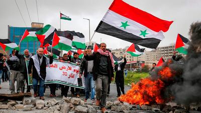 A man waves a Syrian national flag as others wave Palestinian flags behind him while marching during a demonstration marking "Land Day", near the Israeli Jewish settlement of Beit El in the occupied West Bank. AFP