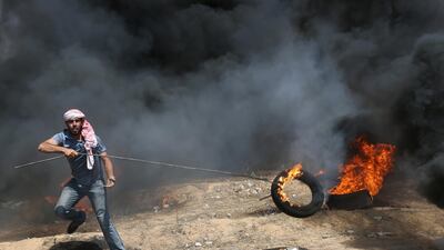A demonstrator drags along a burning tyre. Ibraheem Abu Mustafa / Reuters