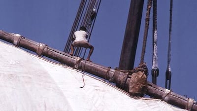 A crew member helps raise the sail.