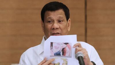 Philippine President Rodrigo Duterte shows a photo of a Filipina worker in Kuwait, who he said had been abused by her employer, during a press conference in Davao City on February 9, 2018. Manman Dejeto / AFP
