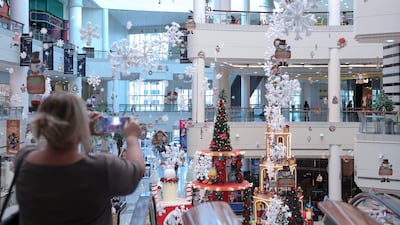 A shopper takes photos of the centre atrium Christmas decoration at Al Wahda Mall, Abu Dhabi. Khushnum Bhandari / The National