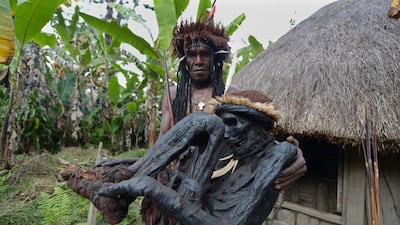 Tribe chief Eli Mabel poses with the mummified remains of his ancestor, Agat Mamete Mabel, outside a traditional house in the village of Wogi in Wamena, the long-isolated home of the Dani tribe high in the Papuan central highlands. Adek Berry/AFP